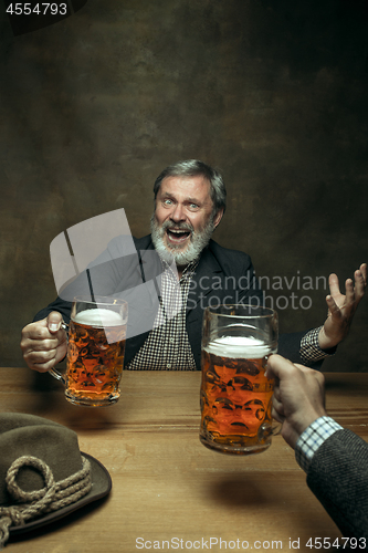 Image of Smiling bearded male drinking beer in pub