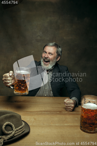 Image of Smiling bearded male drinking beer in pub