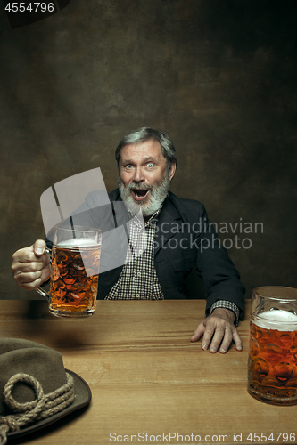 Image of Smiling bearded male drinking beer in pub