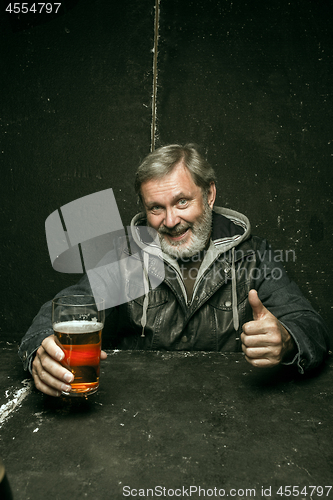 Image of Smiling bearded male drinking beer in pub