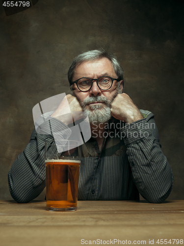 Image of Sad bearded male drinking beer in pub