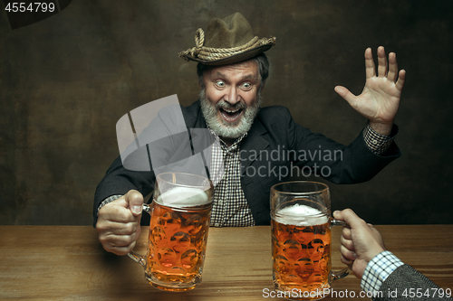 Image of Smiling bearded male drinking beer in pub