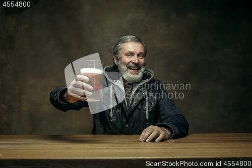 Image of Smiling bearded male drinking beer in pub