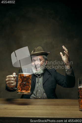 Image of Smiling bearded male drinking beer in pub