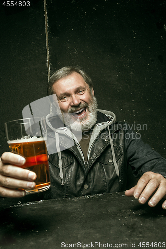 Image of Smiling bearded male drinking beer in pub