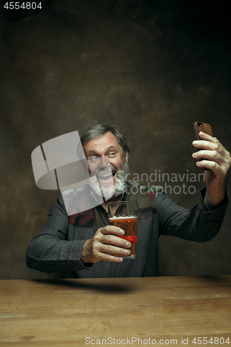 Image of Smiling bearded male drinking beer in pub