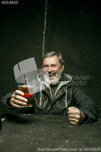 Image of Smiling bearded male drinking beer in pub