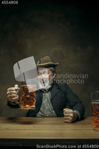 Image of Smiling bearded male drinking beer in pub