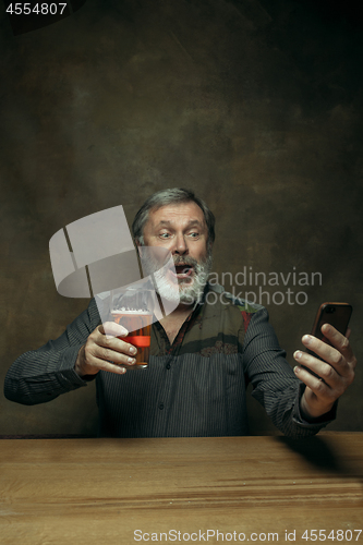 Image of Smiling bearded male drinking beer in pub