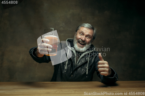 Image of Smiling bearded male drinking beer in pub