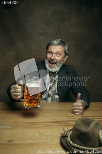 Image of Smiling bearded male drinking beer in pub