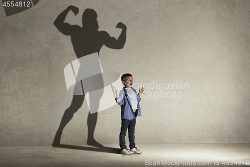 Image of The little boy dreaming about athletic bodybuilder figure with muscles