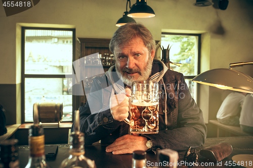 Image of The senior bearded male drinking beer in pub