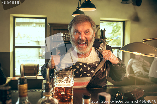 Image of The senior bearded male drinking beer in pub