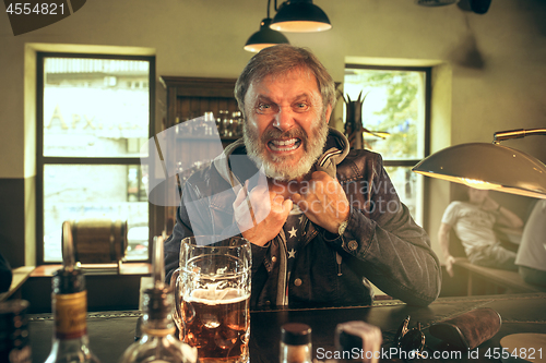 Image of The senior bearded male drinking beer in pub