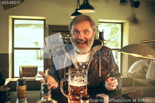 Image of The senior bearded male drinking beer in pub