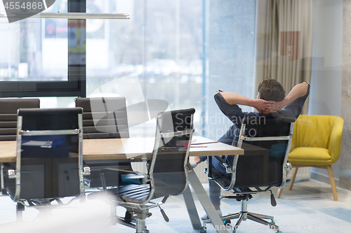 Image of young businessman relaxing at the desk