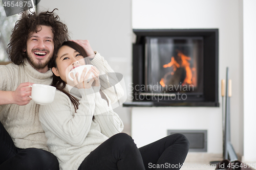 Image of happy multiethnic couple  in front of fireplace