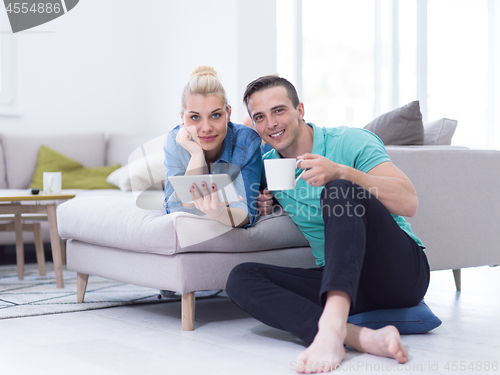 Image of couple relaxing at  home with tablet computers