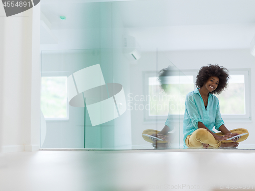 Image of black women using tablet computer on the floor at home