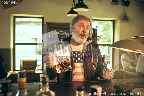 Image of The senior bearded male drinking beer in pub