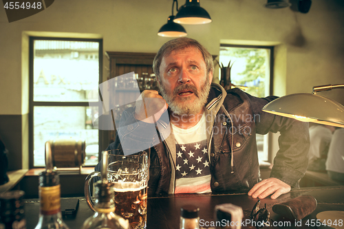 Image of The senior bearded male drinking beer in pub