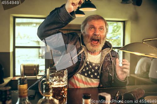 Image of The senior bearded male drinking beer in pub