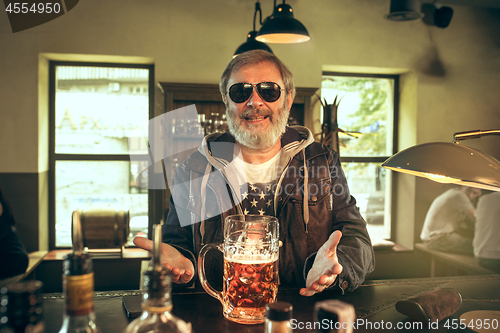 Image of The senior bearded male drinking beer in pub