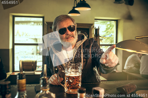 Image of The senior bearded male drinking beer in pub