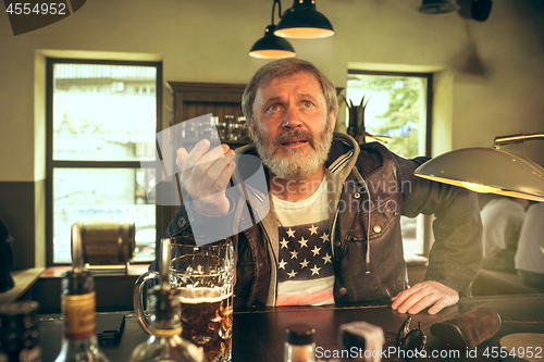 Image of The senior bearded male drinking beer in pub