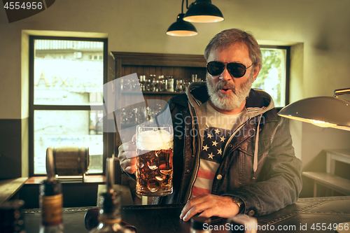 Image of The senior bearded male drinking beer in pub