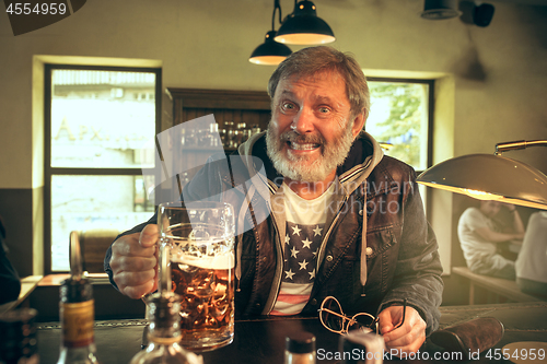 Image of The senior bearded male drinking beer in pub