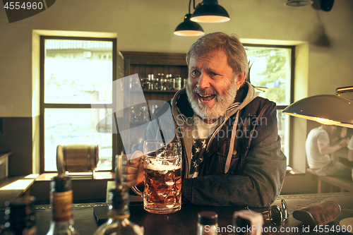 Image of The senior bearded male drinking beer in pub