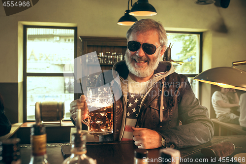 Image of The senior bearded male drinking beer in pub