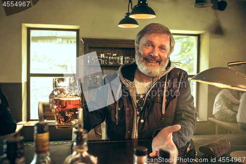 Image of The senior bearded male drinking beer in pub