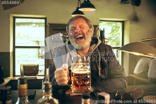 Image of The senior bearded male drinking beer in pub