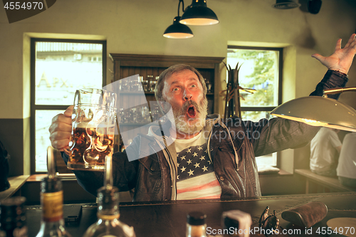 Image of The senior bearded male drinking beer in pub