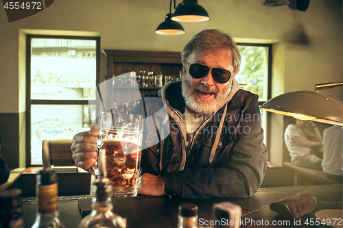 Image of The senior bearded male drinking beer in pub