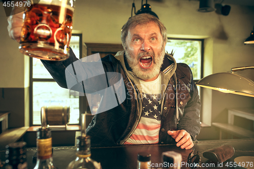 Image of The senior bearded male drinking beer in pub