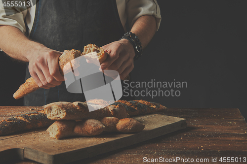 Image of The baker keeps the baguette halves in his hands.