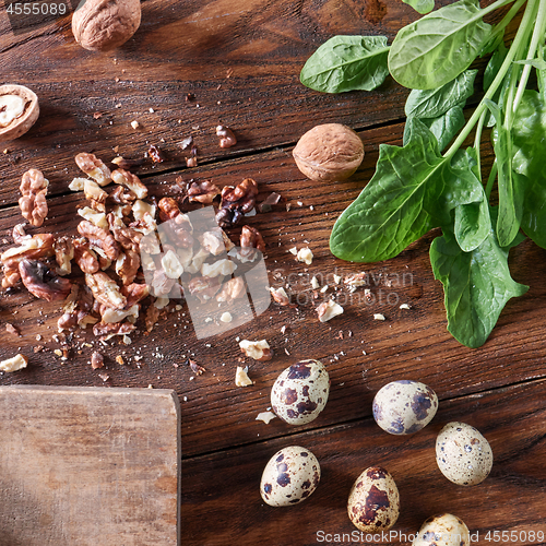 Image of Fresh spinach, quail eggs, pieces of nuts on a wooden table with copy space. Healthy Salad Ingredients. Flat lay