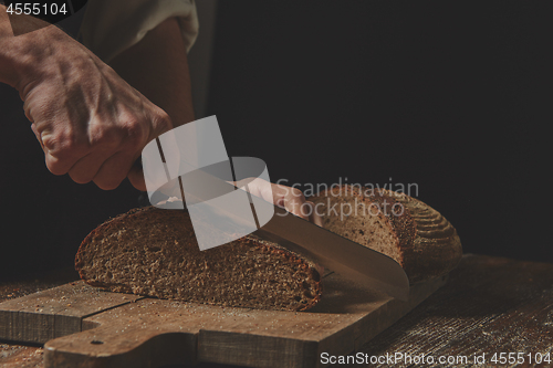 Image of Hands cutting rye bread