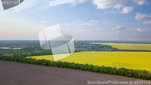 Image of Panoramic view of a field and a village in the distance against a blue sky. Photo from the drone