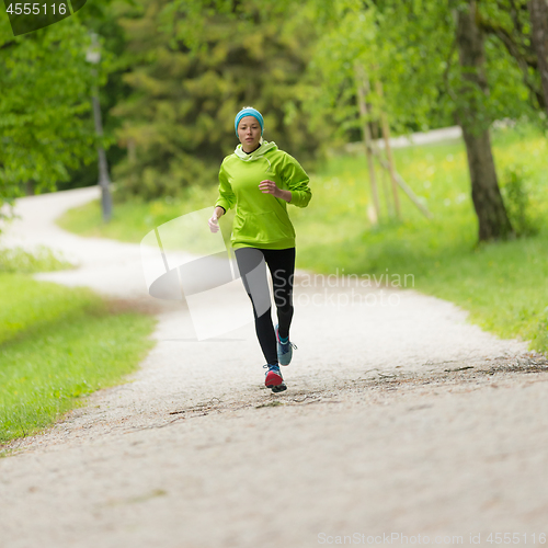 Image of Sporty young female runner in city park..