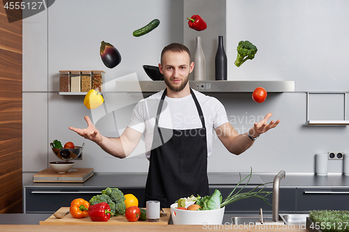 Image of man in the kitchen juggling with vegetables