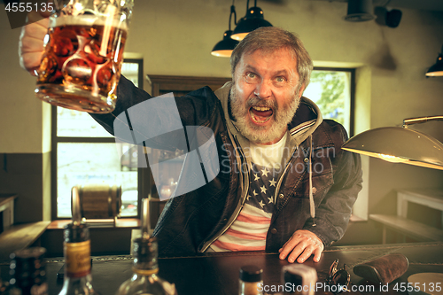 Image of The senior bearded male drinking beer in pub