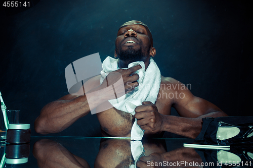 Image of young man in bedroom sitting in front of the mirror after scratching his beard