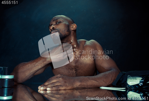 Image of young man in bedroom sitting in front of the mirror after scratching his beard