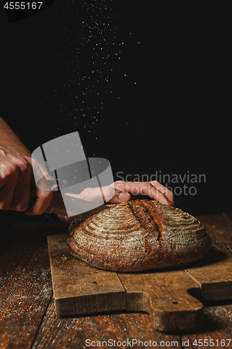 Image of fresh organic bread cut a man\'s hands