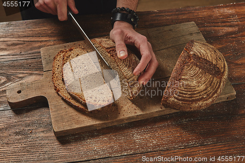 Image of Hands cutting rye bread